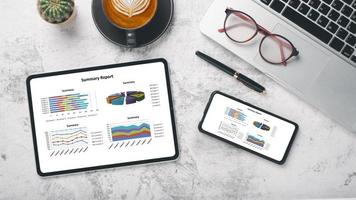 tablette et smartphone avec graphiques et rapports sur le lieu de travail de bureau. vue de dessus mise à plat photo