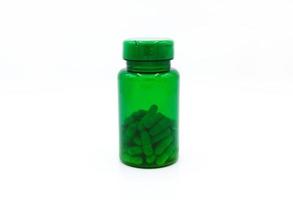 bouteille en plastique vert de pilules ou capsules isolées sur fond blanc. aliments sains, herbes, objet contenant et médicament e. compléments alimentaires pour soigner ou réparer la santé. photo