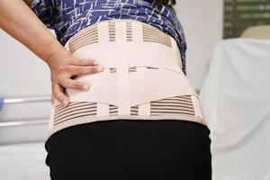 une personne âgée asiatique portant une ceinture de soutien élastique peut aider à réduire les maux de dos. photo