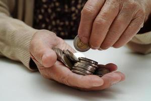 une femme âgée à la retraite comptant des pièces de monnaie et s'inquiète des dépenses mensuelles et du paiement des frais de traitement. photo