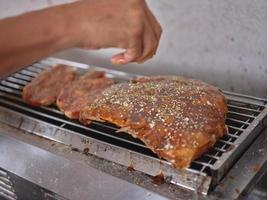 le chef verse le poivre d'épices dans les côtes de porc grillées photo