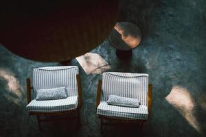 vue de dessus sur l'intérieur du salon sombre avec table basse et chaise sur sol en béton. photo