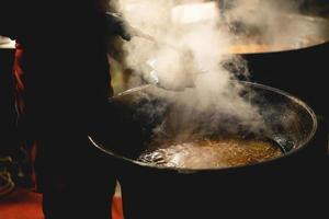 le cuisinier remplit un bol de nourriture de rue chaude photo