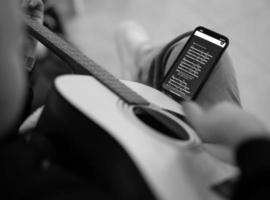 musicien jouant de la guitare acoustique en regardant les accords au téléphone. photo