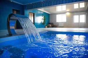 une grande piscine intérieure moderne avec un éclairage bleu et une cascade. photo