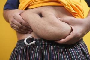 main de l'homme tenant la graisse du ventre excessive, concept de surpoids photo