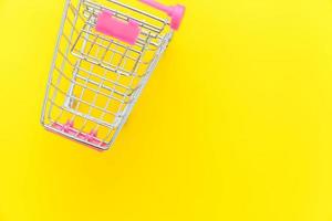 petit chariot d'épicerie de supermarché pour faire du shopping jouet avec roues isolé sur fond de mode moderne tendance coloré jaune. vente acheter concept de consommateur de magasin de marché de centre commercial. espace de copie. photo