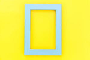 concevez simplement avec un cadre bleu vide isolé sur un fond tendance coloré jaune. vue de dessus, mise à plat, espace de copie, maquette. notion minimale. photo