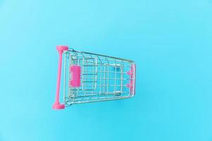petit chariot d'épicerie de supermarché pour faire du shopping jouet avec roues isolées sur l'espace de copie de fond tendance coloré pastel bleu. vente acheter concept de consommateur de magasin de marché de centre commercial. photo