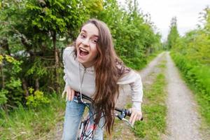 jeune femme à vélo dans le parc de la ville d'été à l'extérieur. personnes actives. fille hipster se détendre et faire du vélo photo