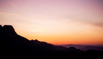 coucher de soleil violet et orange romantique sur les hautes tatras avec une brume dense et de longs rayons de soleil. lever de soleil vibrant et coloré depuis le sommet. trekking pendant l'heure d'or dans la forêt. photo