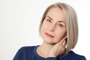 Jolie femme d'âge moyen avec les bras croisés sur fond blanc photo