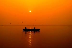 silhouette de pêcheurs avec soleil jaune et orange en arrière-plan photo