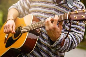 un gars joue de la guitare dans le parc de la ville en plein air photo