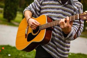 un gars joue de la guitare dans le parc de la ville en plein air photo