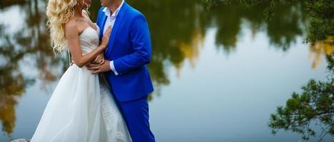 un jeune couple de jeunes mariés dans leurs robes de mariée se tient au rocher photo