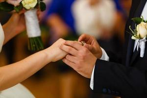 les jeunes mariés échangent des bagues, le marié met la bague sur la main de la mariée au bureau d'enregistrement des mariages photo