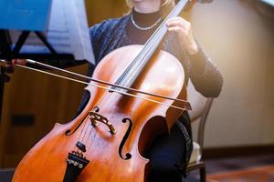 une jeune fille joue du violoncelle dans le noir. mains sur le violoncelle photo