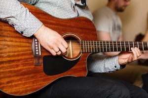 jeune musicien jouant de la guitare acoustique en gros plan photo