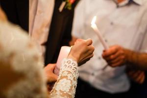 une bougie entre les mains d'un couple de jeunes mariés. mariage au monténégro. photo