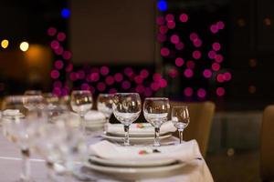 belle table avec vaisselle et fleurs pour une fête, réception de mariage ou autre événement festif. verrerie et couverts pour le dîner d'événement traiteur. photo