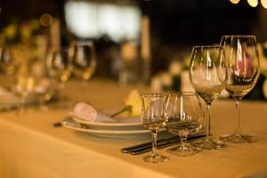 belle table avec vaisselle et fleurs pour une fête, réception de mariage ou autre événement festif. verrerie et couverts pour le dîner d'événement traiteur. photo
