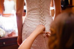 demoiselle d'honneur nouant un arc sur une robe de mariée photo