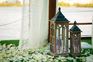 décoration de mariage dans un style rustique.deux lampes vintage blanches avec des fleurs à l'intérieur debout sur l'herbe verte photo