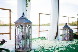 décoration de mariage dans un style rustique.deux lampes vintage blanches avec des fleurs à l'intérieur debout sur l'herbe verte photo