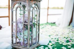 décoration de mariage dans un style rustique.deux lampes vintage blanches avec des fleurs à l'intérieur debout sur l'herbe verte photo