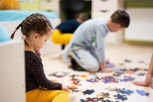 enfants connectant des pièces de puzzle dans une chambre d'enfants au sol à la maison. loisirs amusants en famille. photo