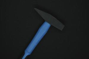 marteau de construction sur fond noir. un marteau de charpentier avec un manche bleu sur fond noir. photo