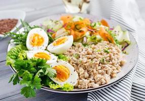 bol de petit déjeuner avec flocons d'avoine, courgettes, laitue, carotte et œuf à la coque. salade fraiche. la nourriture saine. bol bouddha végétarien. photo