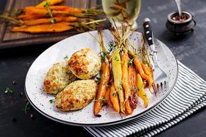 carottes biologiques cuites au four avec thym et escalope, viande de poulet aux boulettes de viande et courgettes. nourriture diététique. photo