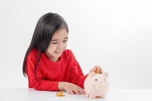 petite fille asiatique économisant de l'argent dans une tirelire, apprenant à économiser, enfant économisant de l'argent pour l'éducation future. concept d'argent, de finances, d'assurance et de personnes