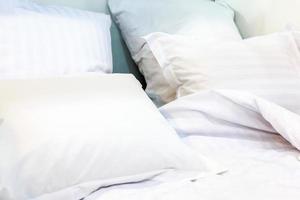 femme de chambre avec oreillers blancs propres et draps de lit dans la salle de beauté. fermer. flair de l'objectif à la lumière du soleil. photo