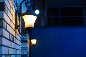 lanterne sur le mur de briques de la vieille ville, flou de nombreuses lampes sur pilier photo