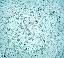 gel avec des bulles d'oxygène. fond liquide transparent bleu abstrait. gel antibactérien, acide hyaluronique. gros plan macro photo