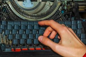 la main d'une femme écrit sur une vieille machine à écrire. photo