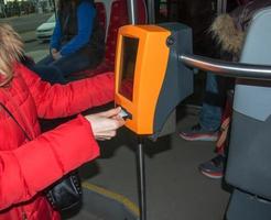 jeune femme élégante à l'aide d'une poinçonneuse de billets dans les transports publics. la fille frappe le billet. photo