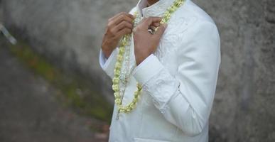 marié tenant un collier de fleurs de jasmin et de magnolia cérémonie de mariage traditionnelle photo