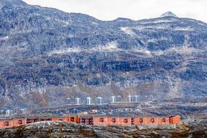 rangées de maisons inuit modernes colorées parmi les pierres moussues avec des pentes abruptes grises de la petite montagne malène en arrière-plan, nuuk, groenland photo