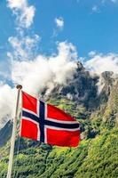 drapeau national norvégien agitant dans le vent et le sommet de la montagne dans le fjord de neroy, aurlan, comté de sogn og fjordane, norvège photo