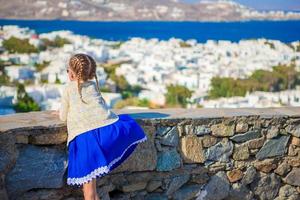 adorable petite fille dans la ville de mykonos fond vue imprenable sur les maisons blanches traditionnelles photo