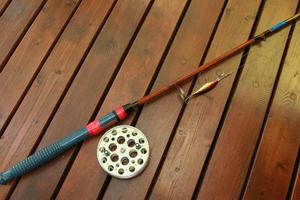 canne à pêche vintage avec un gros moulinet et un wobbler sur un fond en bois photo