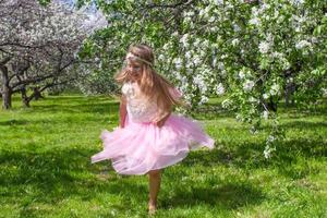 adorable petite fille s'amuse dans un verger de pommiers en fleurs photo