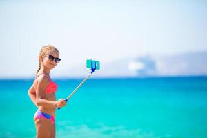 petite fille prenant l'autoportrait par son smartphone sur la plage. enfant profitant de ses vacances d'été et faisant des photos de fond la mer