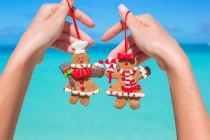 gros plan de biscuits de pain d'épice de noël dans les mains contre la mer turquoise photo