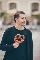 beau jeune homme tenant un bretzel et se relaxant dans le parc photo