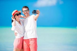 couple prenant selfie sur la plage. touristes personnes prenant des photos de voyage pendant les vacances d'été.